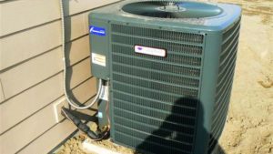 heat pump located on the exterior wall of a home with siding. 