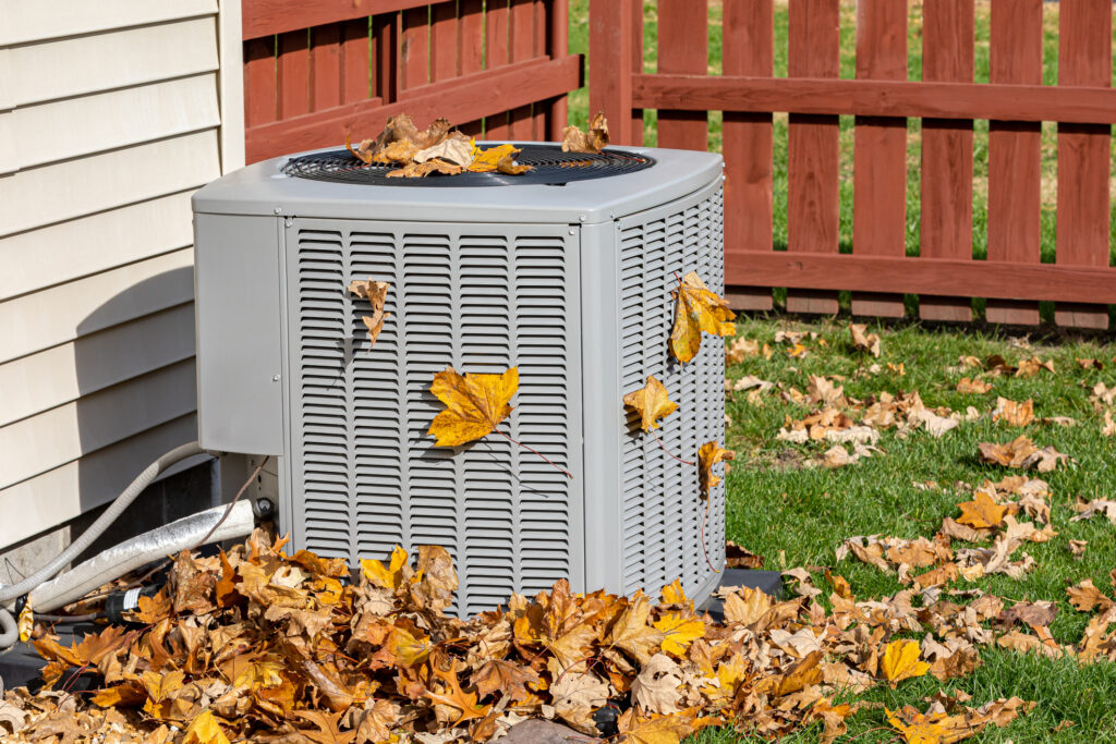 Outdoor HVAC unit covered with autumn leaves